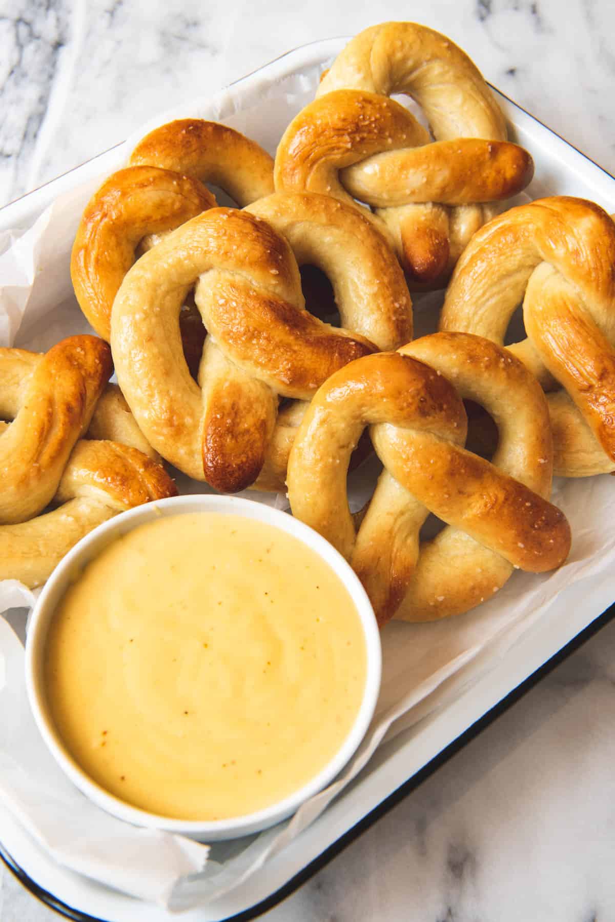 An image of a bowl of easy homemade cheese dipping sauce with warm soft pretzels.