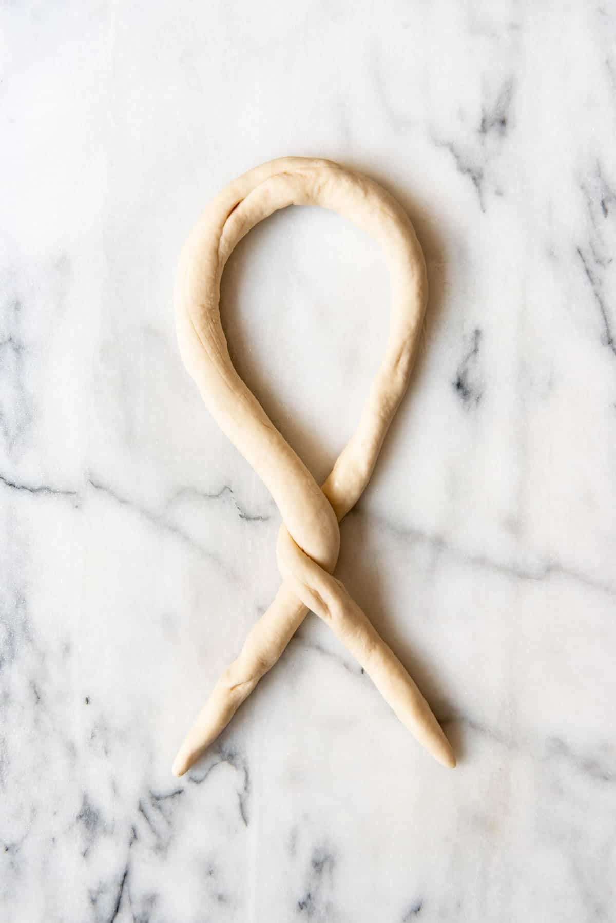 An image of a pretzel  dough rope getting ready to be twisted.