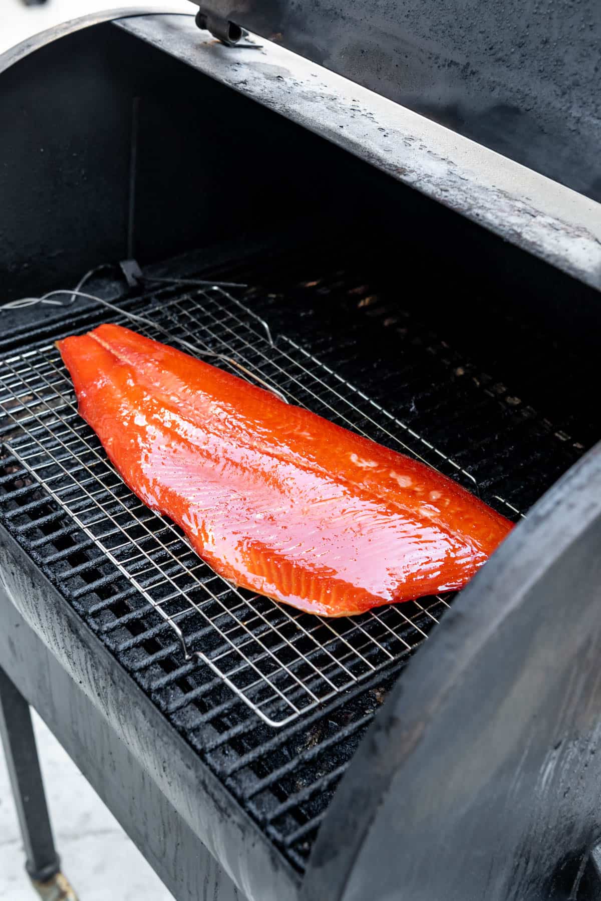 An image of a large piece of salmon on a pellet smoker.
