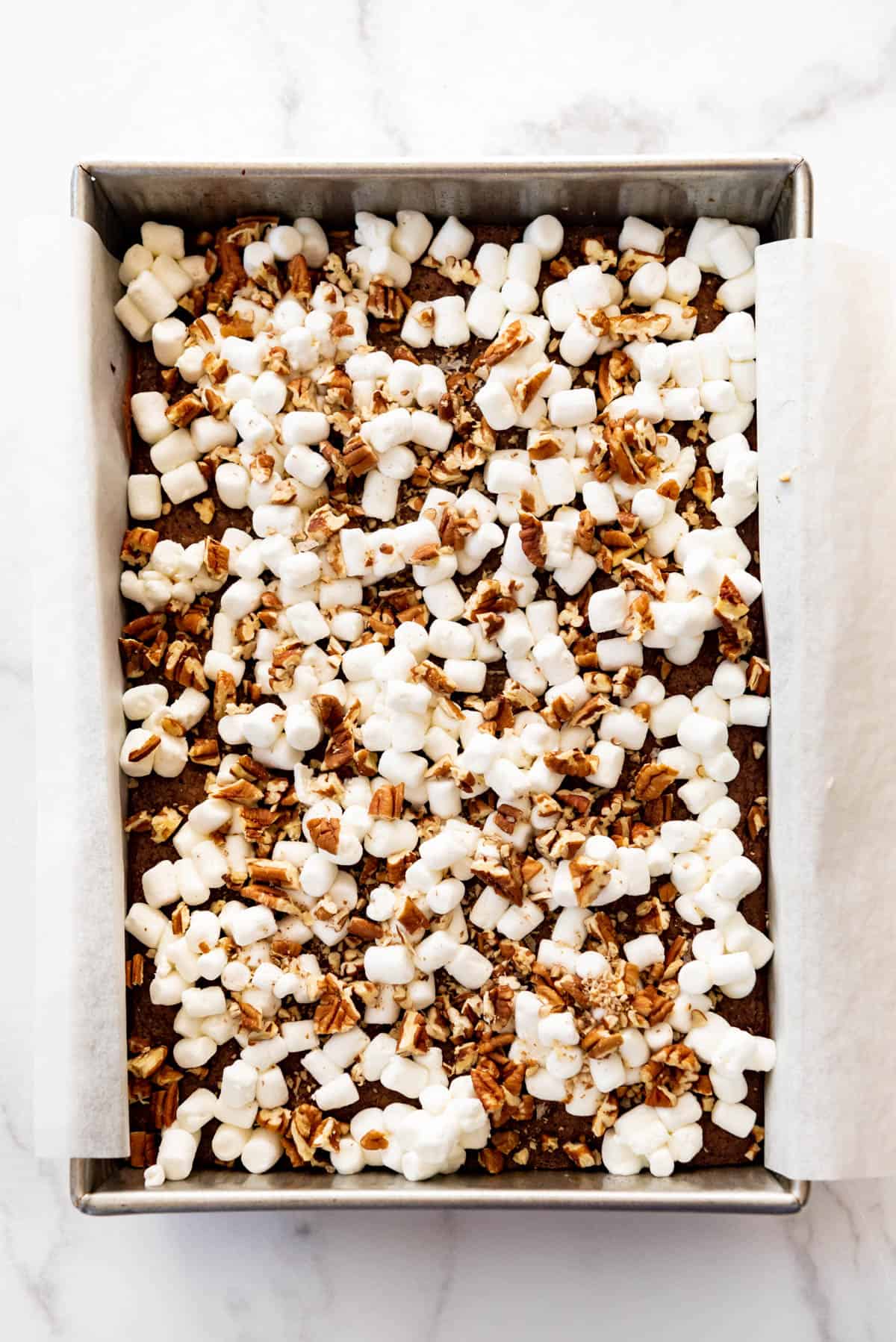 Chopped pecans sprinkled on top of marshmallows and brownies.
