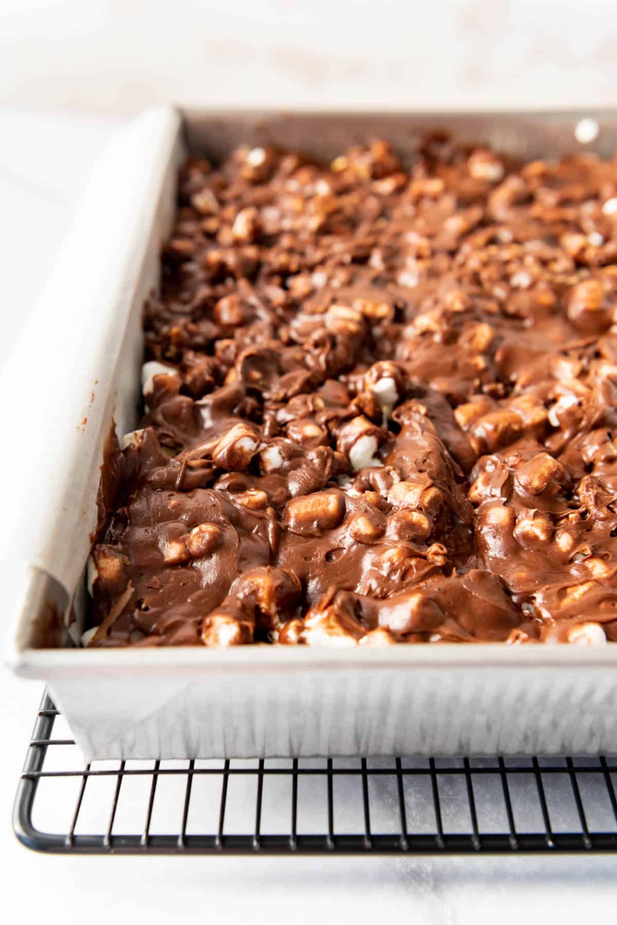 A pan of frosted brownies with marshmallows and pecans.