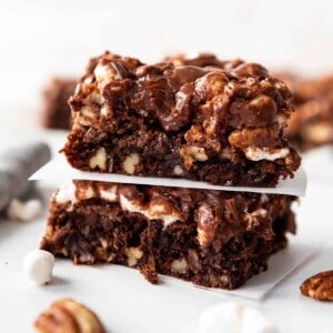 Two Mississippi Mud Brownies stacked on top of each other with a square of parchment paper between them.
