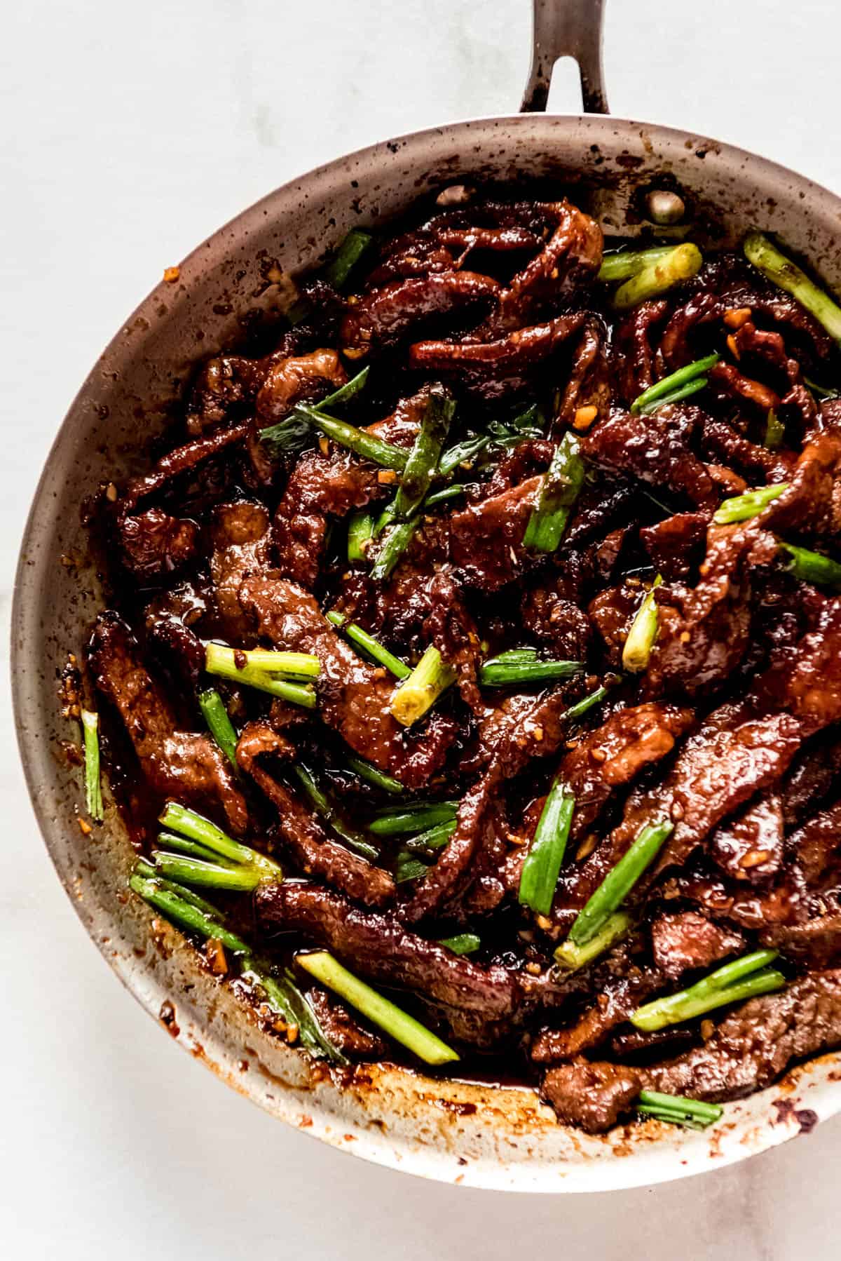 Mongolian Beef Recipe in pan cooked with sauce and green onions roughly chopped and sprinkled on top of beef.
