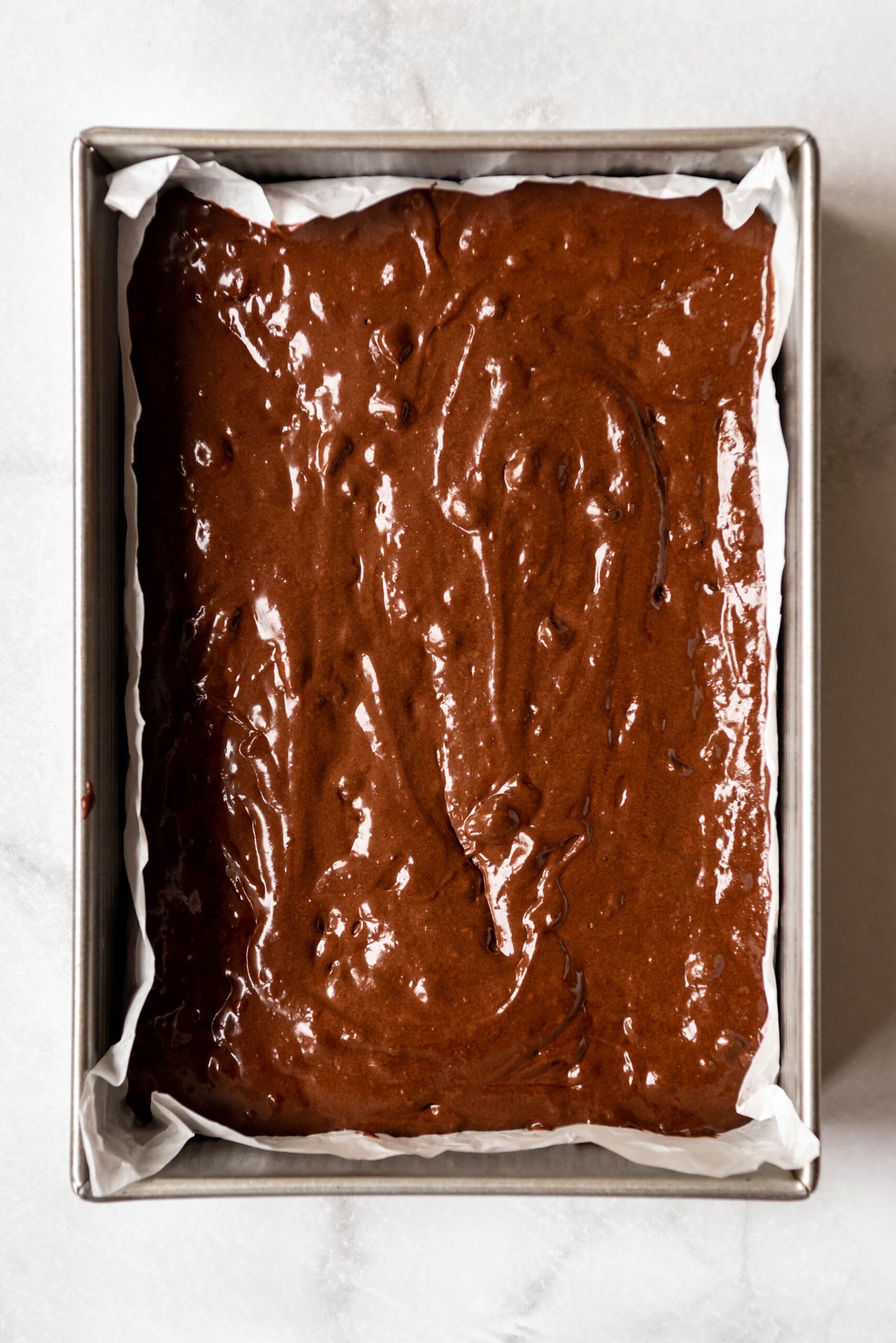 Brownie batter spread in a 9x13-inch baking dish.