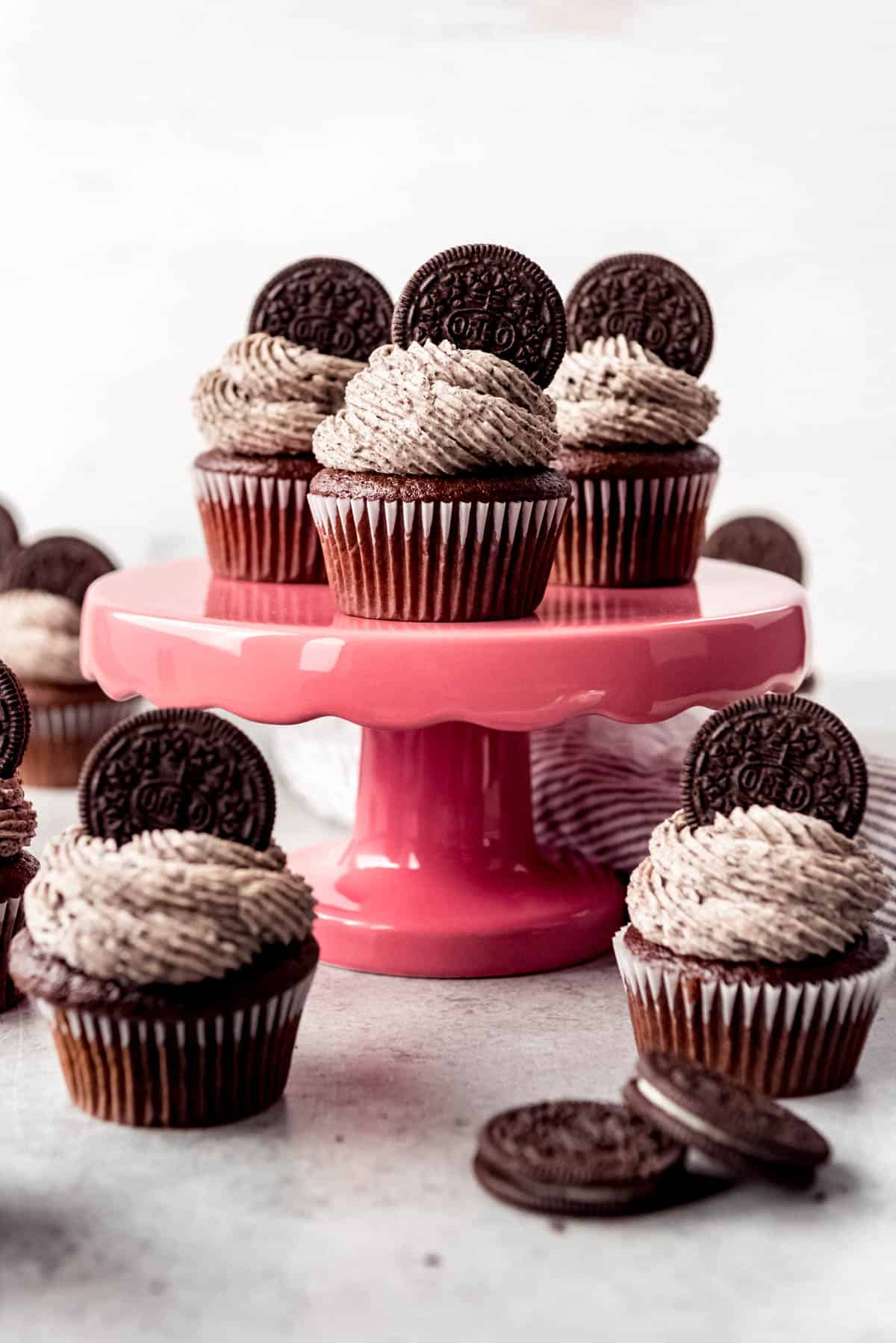An image of chocolate cupcakes on cake stand with Oreo frosting and whole Oreos decorating the tops.