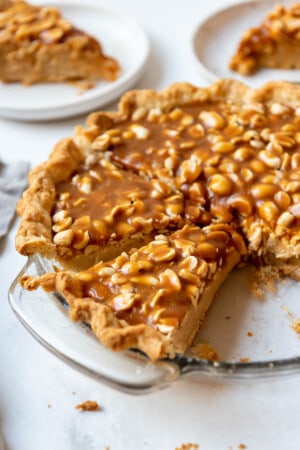 A partially sliced Payday Pie in a glass pie plate.