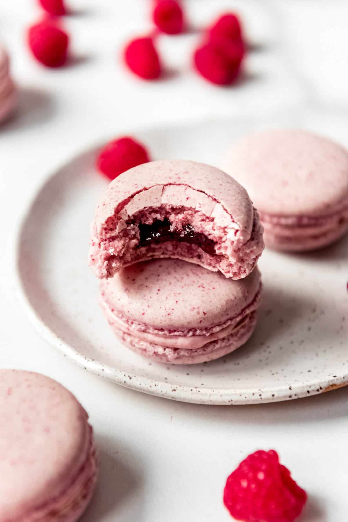 An image of a French macaron with a bite taken out of it to show jam filling in the middle.