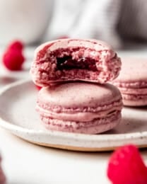 Raspberry Macaron on plate with a bite taken out of it.