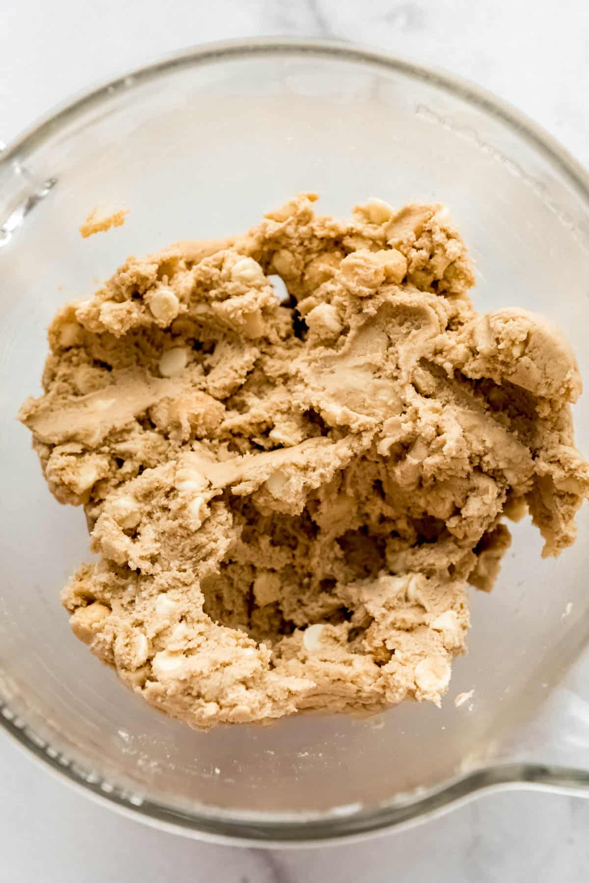 White chocolate macadamia nut cookie dough in a glass mixing bowl.