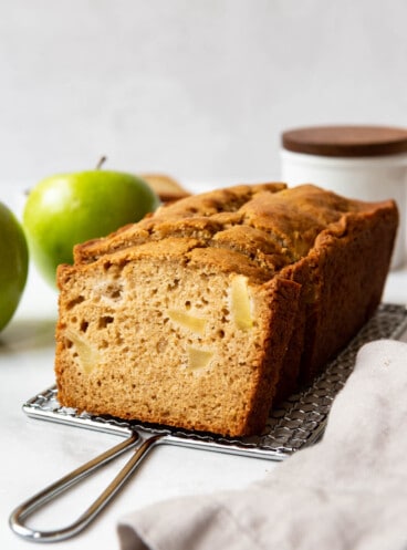 A loaf of apple ginger quick bread on a wire cooling rack.