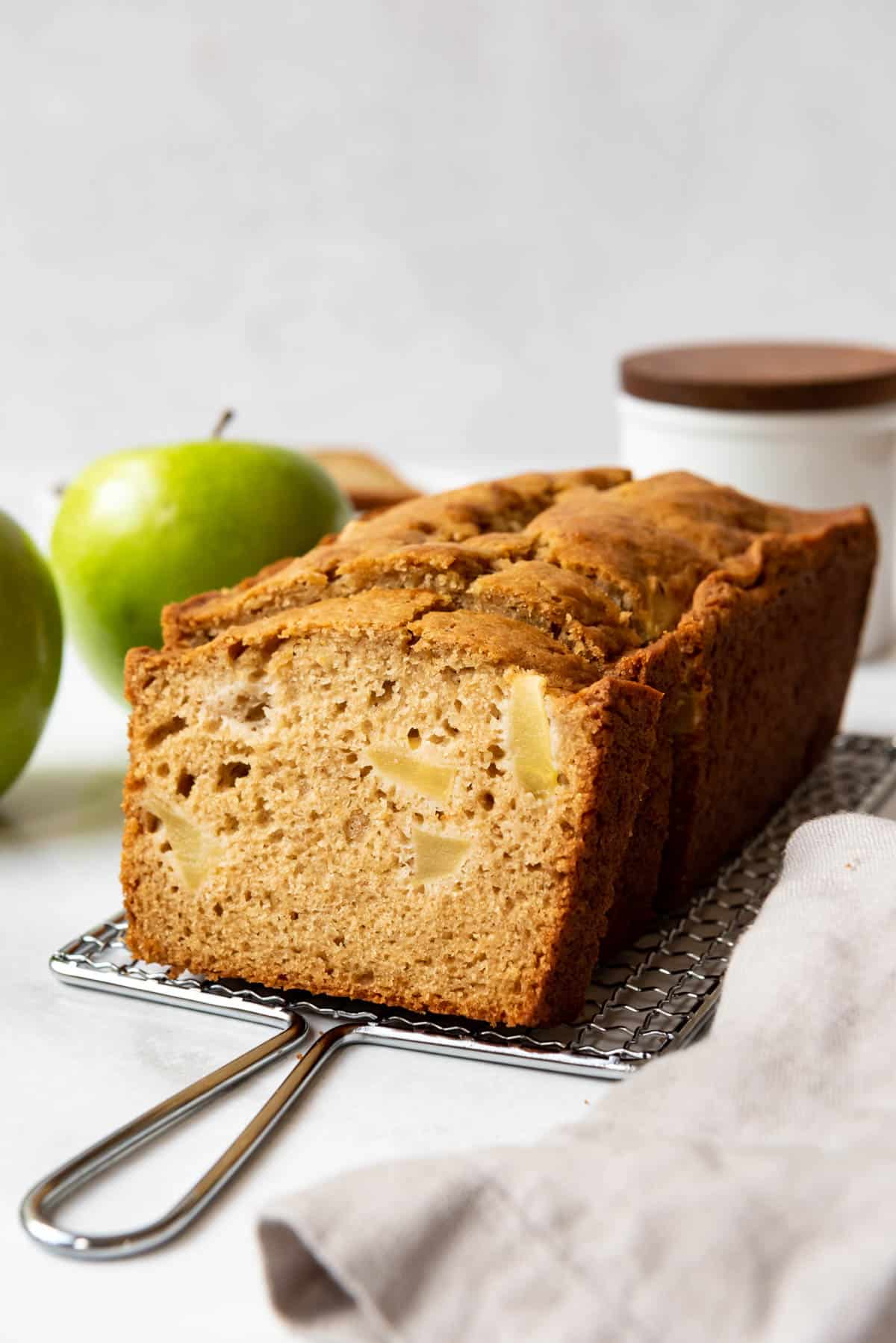 A loaf of apple ginger quick bread on a wire cooling rack.