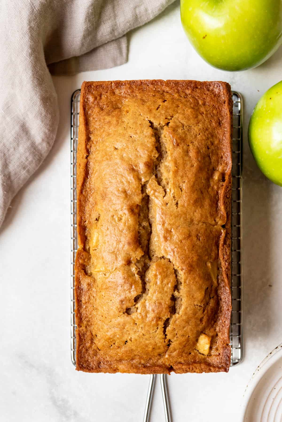 A loaf of apple ginger quick bread next to granny smith apples.