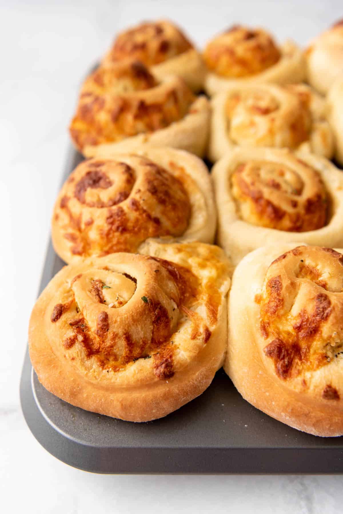 Baked savory garlic cheese rolls in a muffin pan.