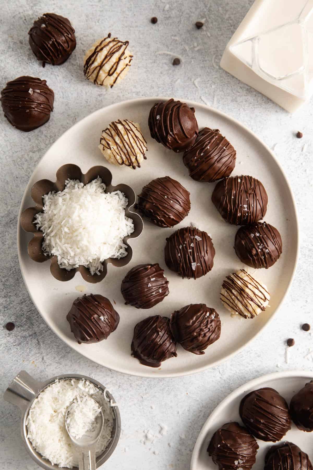 An overhead image of a plate of chocolate coconut balls that have been decorated with drizzled chocolate.