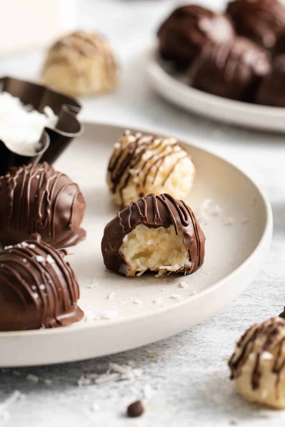An image of Mounds Truffles (aka chocolate coconut balls) on a plate with a bite taken out of one of them.