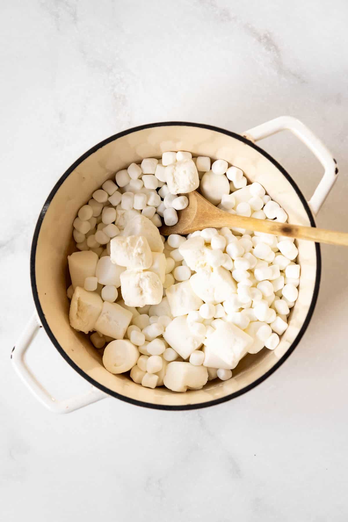 Adding marshmallows to melted butter in a large pot.