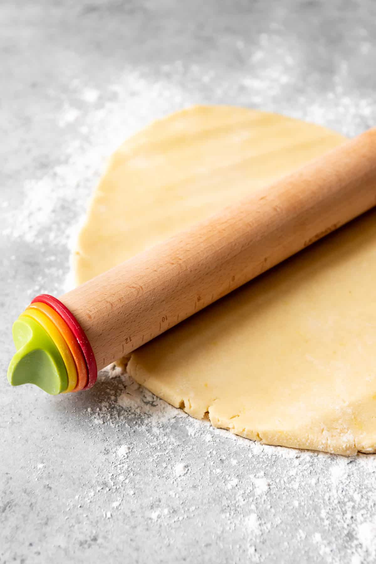 A rolling pin on top of sugar cookie dough.
