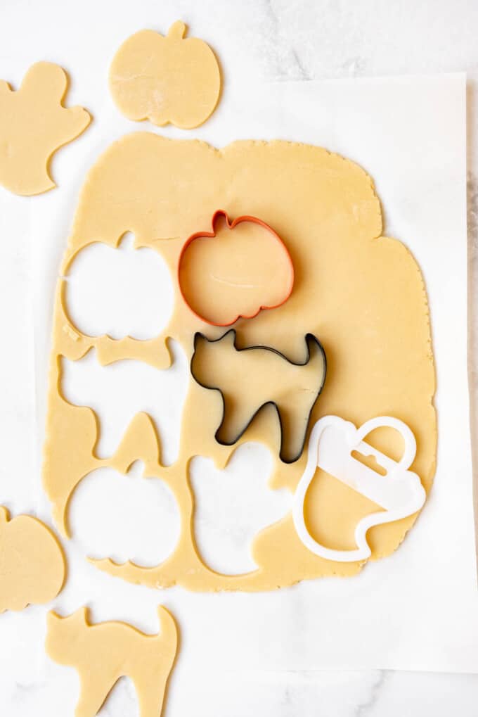Cutting out sugar cookie dough with Halloween cookie cutters.
