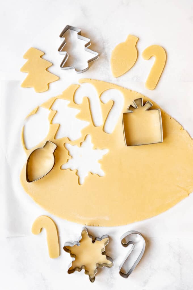 Cutting out sugar cookie dough with Christmas themed cookie cutters.