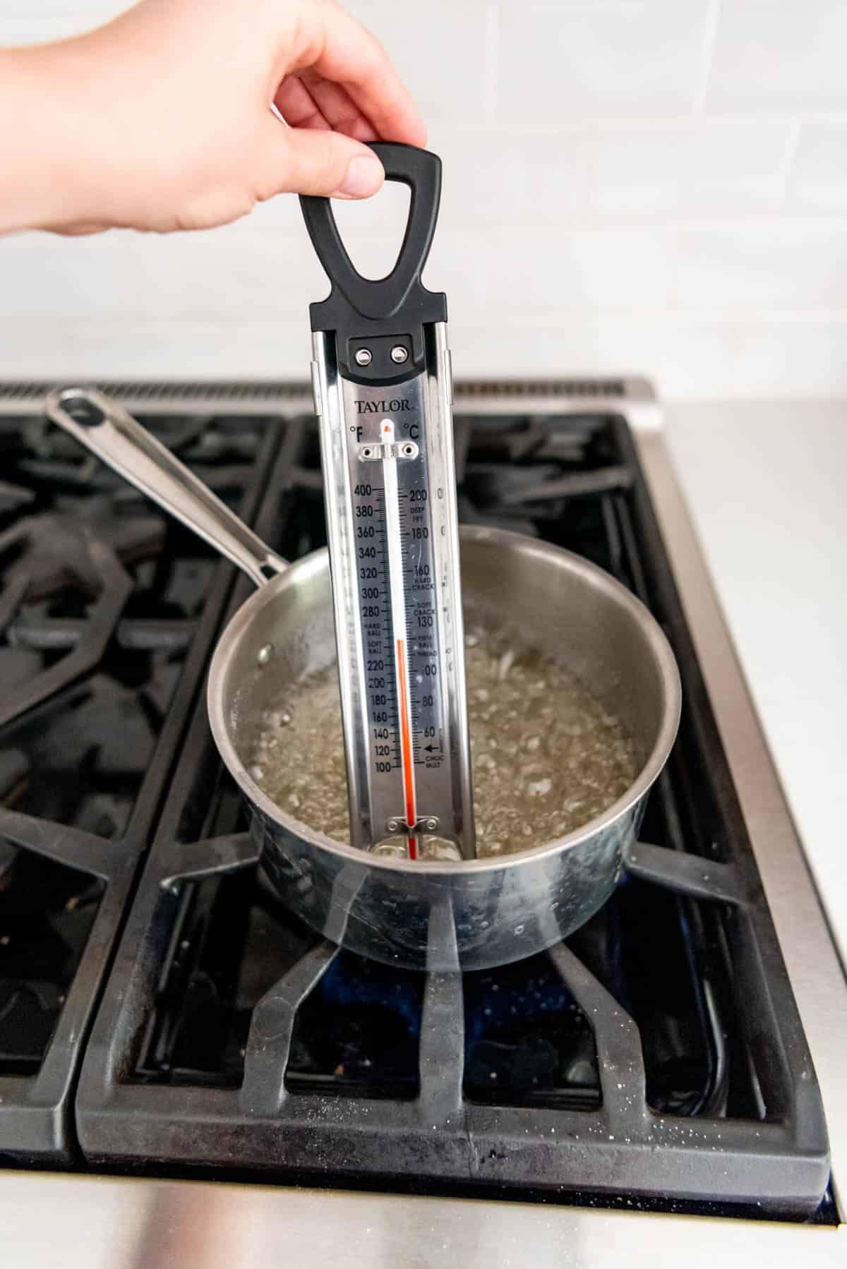 Candy thermometer in a pot of boiling sugar, water and corn syrup for making divinity candy.