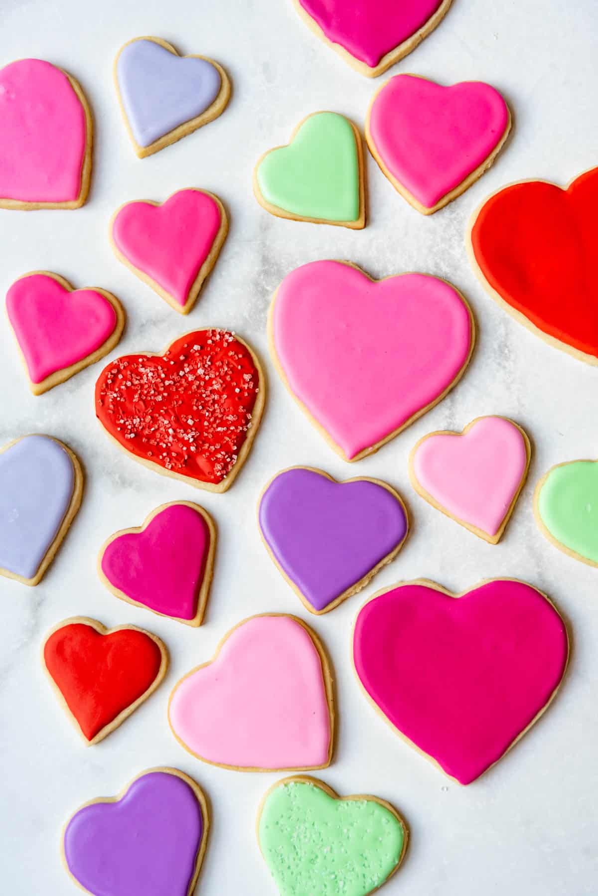 Heart shaped sugar cookies decorated with royal icing in reds, pinks, purples, and greens.