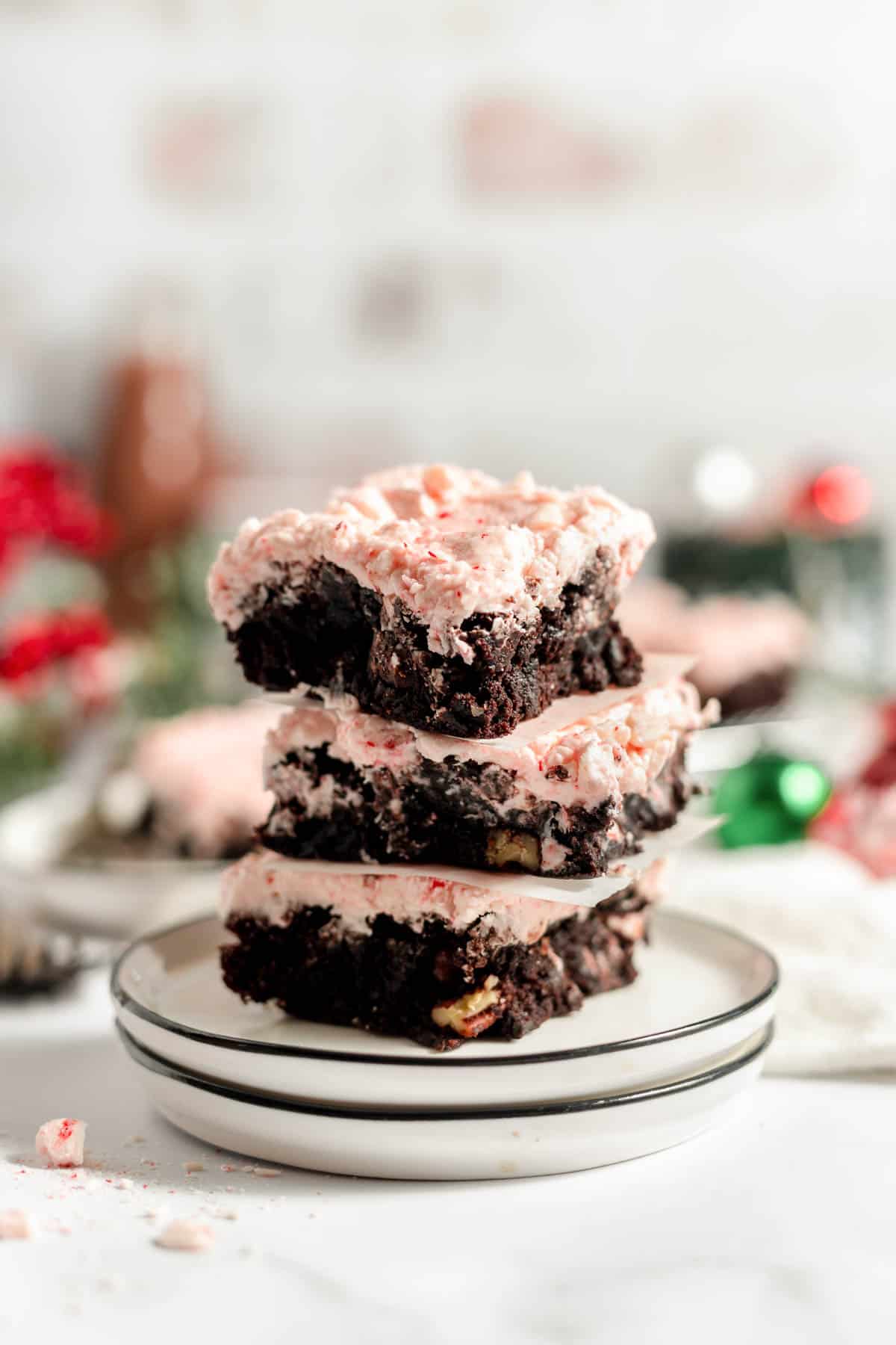 A stack of three frosted peppermint brownies on a plate.