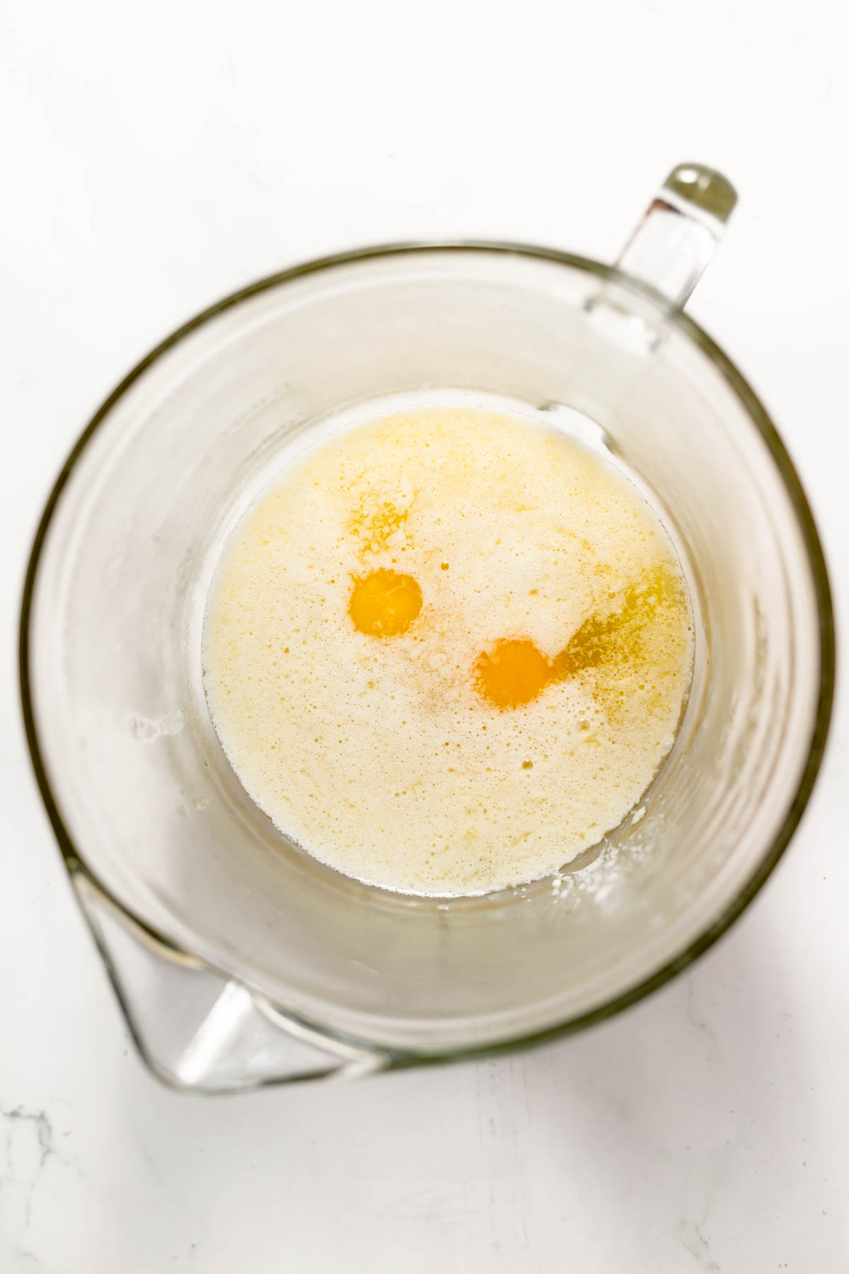 Eggs, milk, and melted butter in a glass mixing bowl.