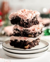 A stack of frosted peppermint brownies on a plate.