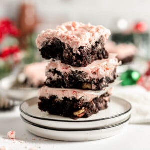 A stack of frosted peppermint brownies on a plate.