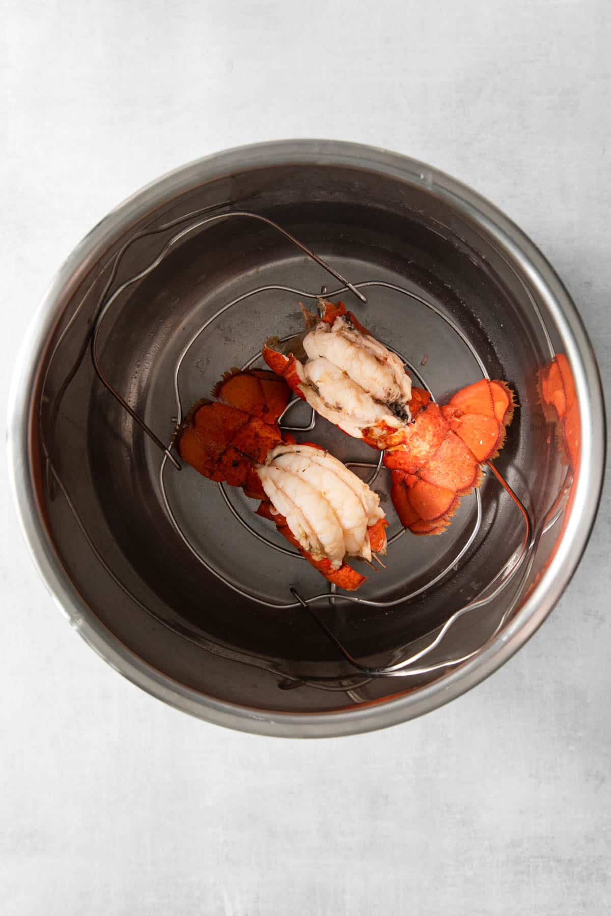 Top view of cooked lobster tails in the bottom of an Instant Pot large pot. 