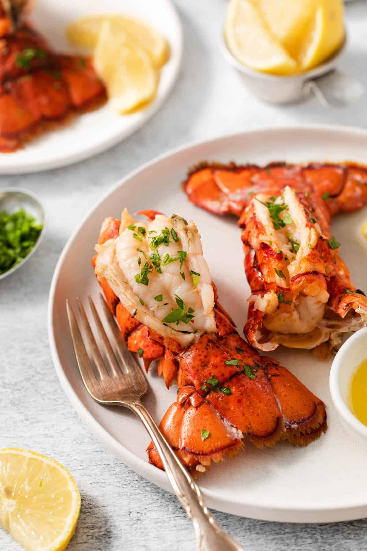 Two lobster tails on a plate with a fork.