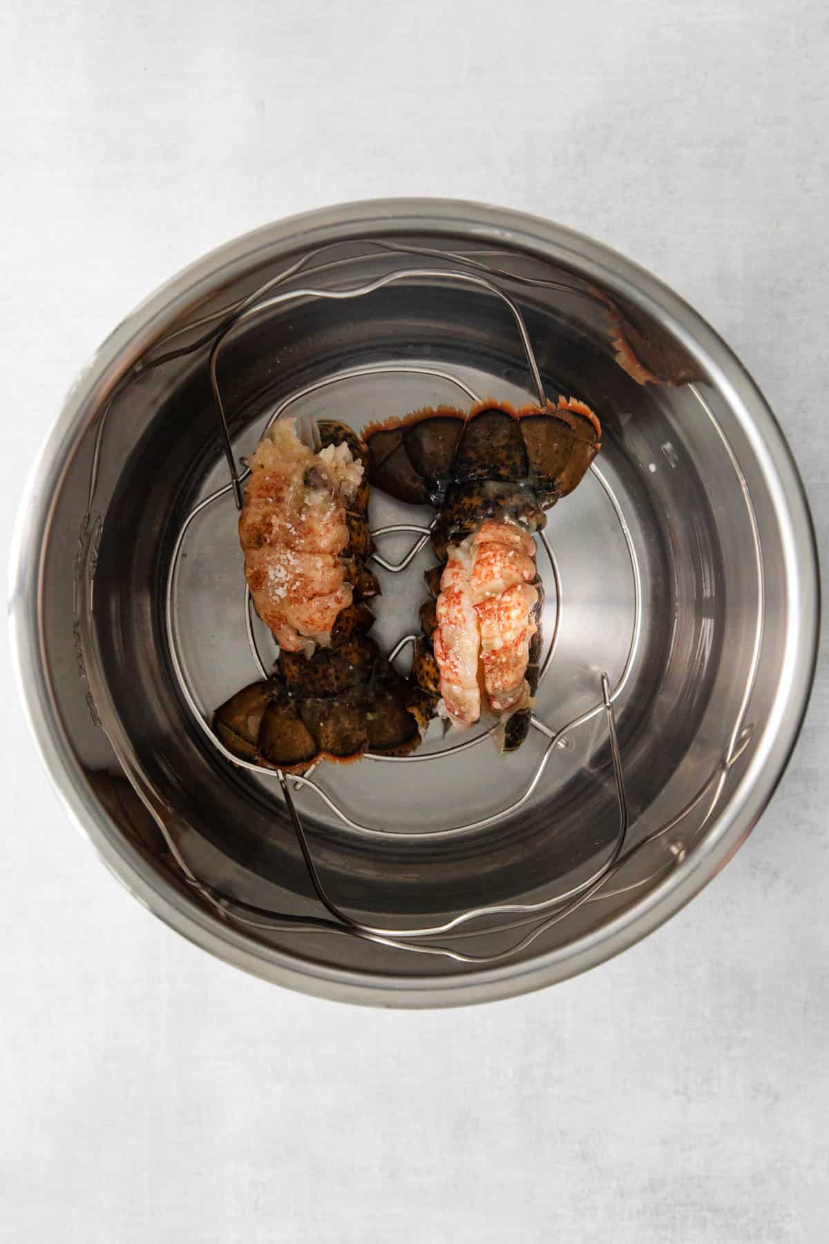 Top view of raw lobster tails in the bottom of an Instant Pot large pot. .