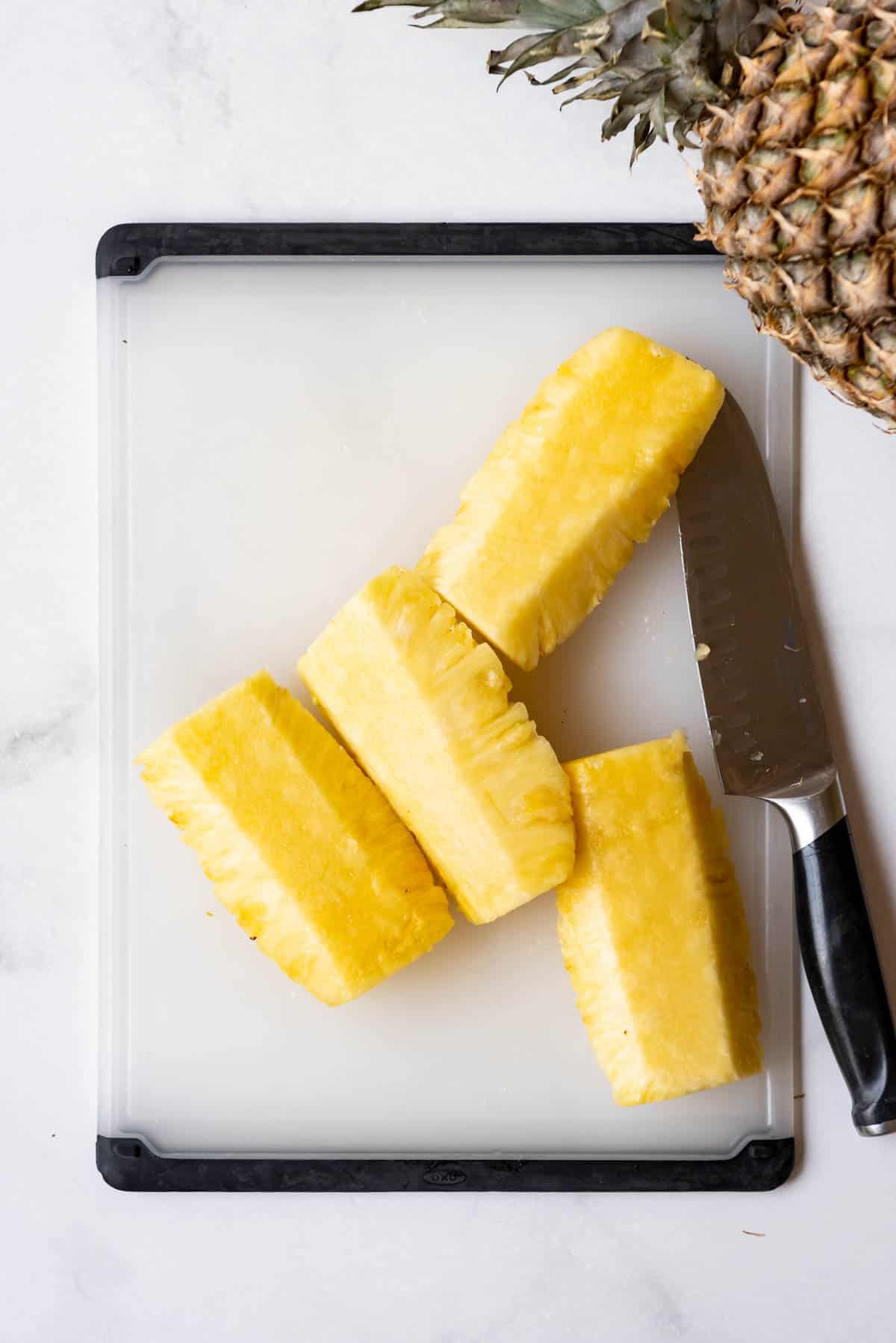 Pineapple spears on a cutting board with a knife.