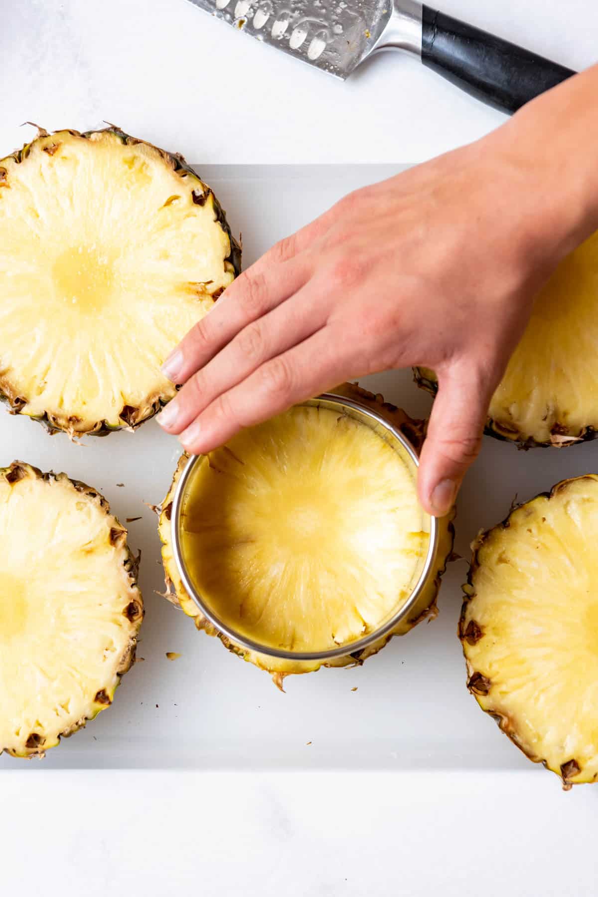 Cutting pineapple rings from freshly sliced pineapple.