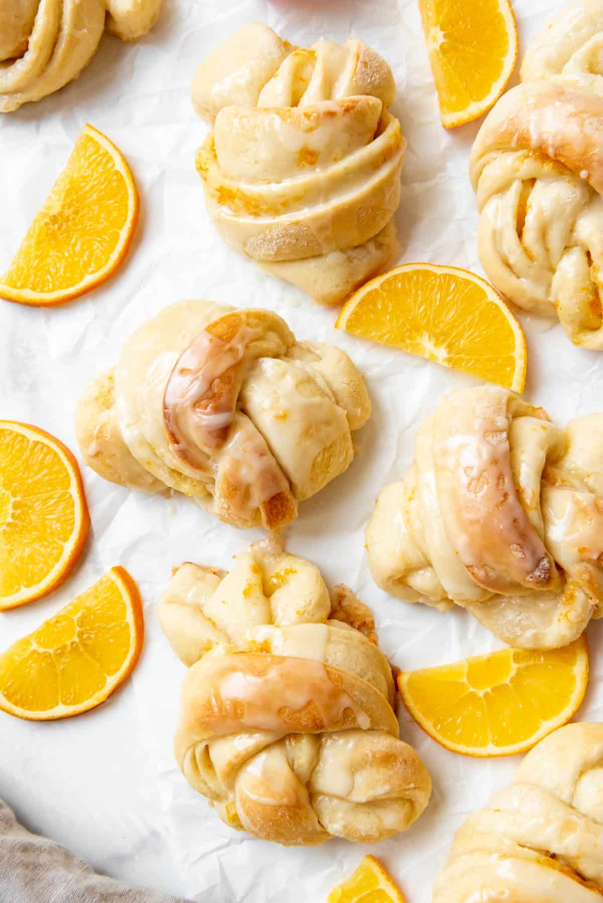 An overhead image of orange sweet rolls with orange slices.