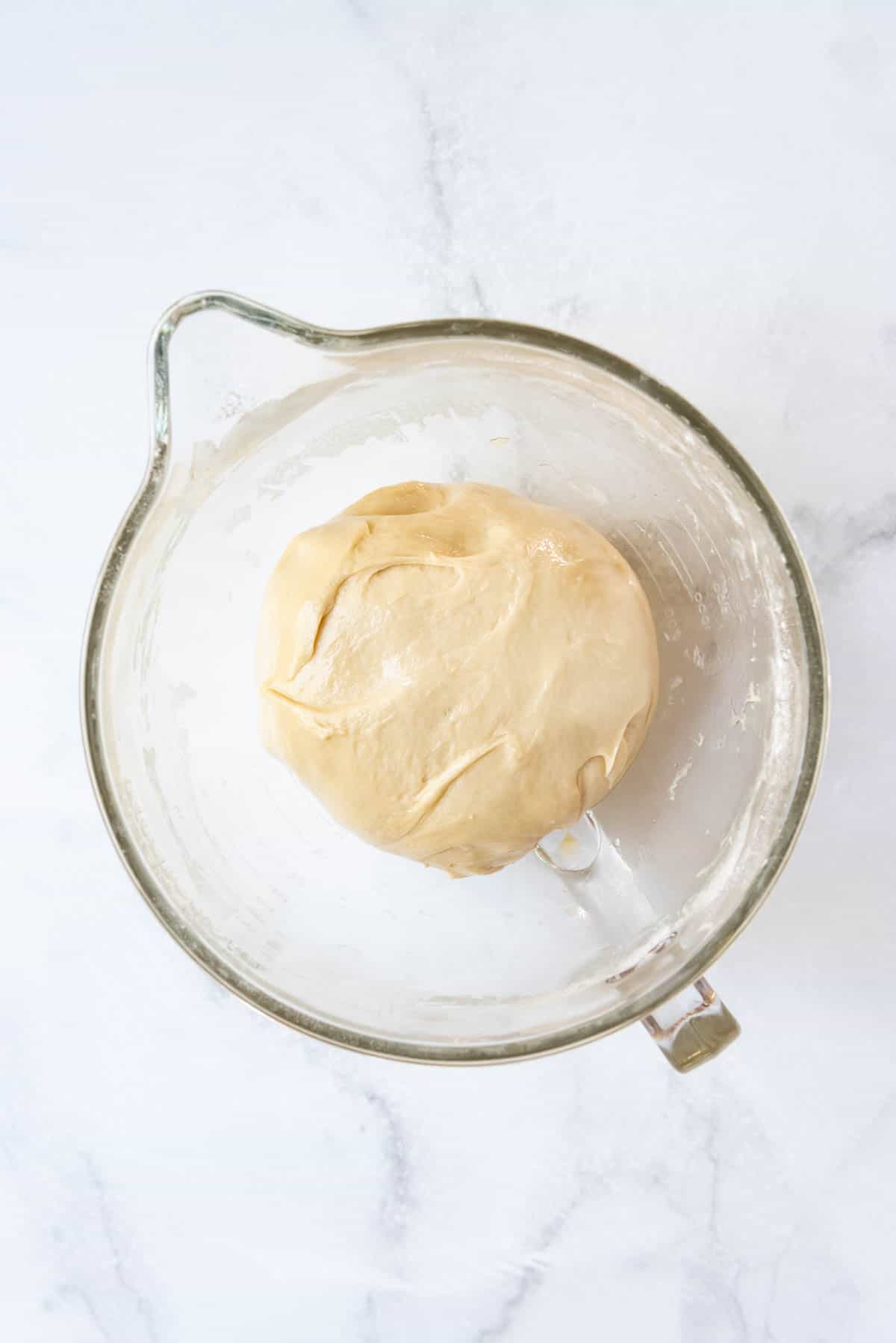 Kneaded yeast dough in a glass bowl ready to rise until doubled in size.