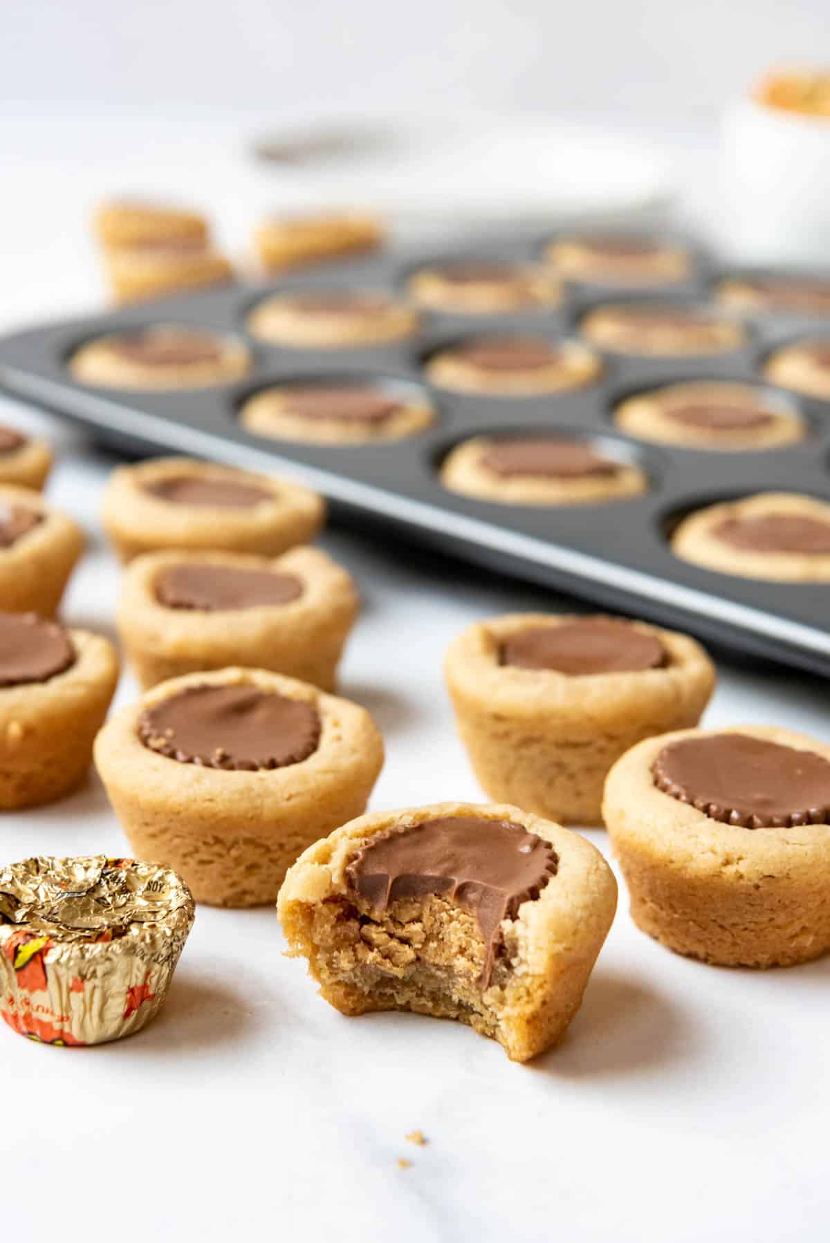 Soft peanut butter cup cookies with a bite taken out of the one in front.