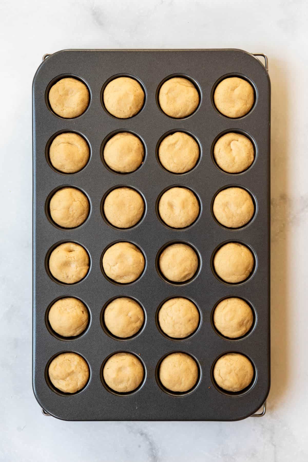 Baked peanut butter cookie dough in a mini muffin pan.