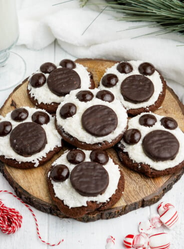 A wooden cutting board with chocolate polar bear paw cookies on it.