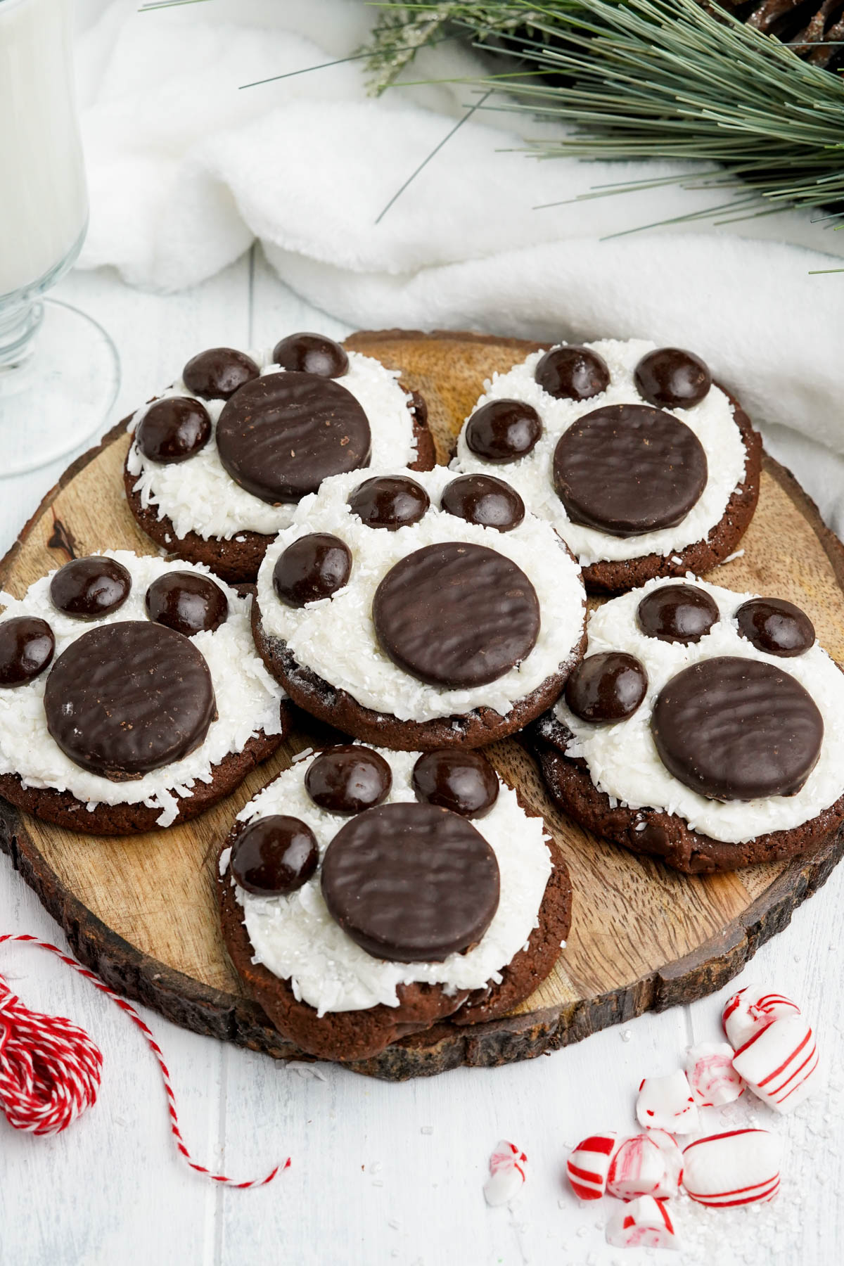 A wooden cutting board with chocolate polar bear paw cookies on it.