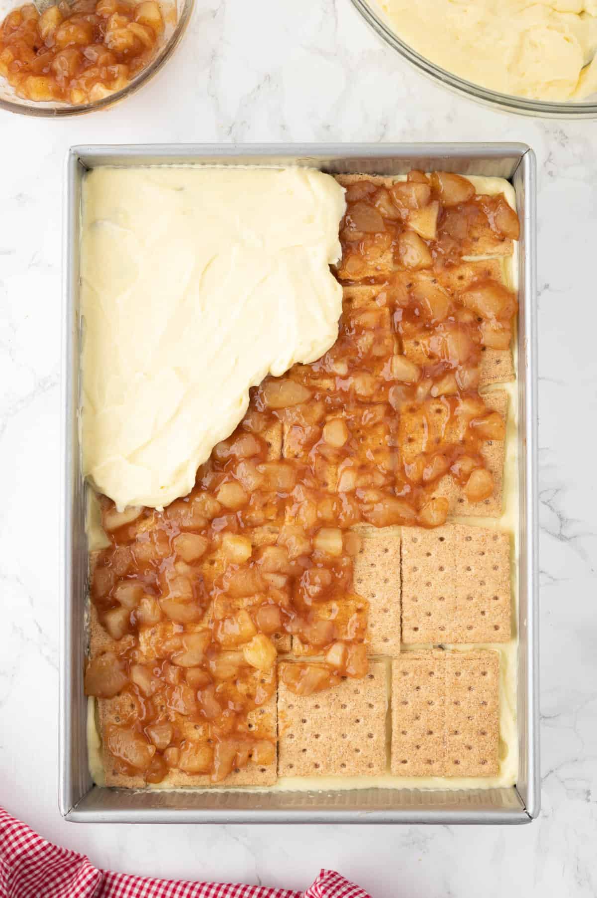 Adding layers of graham cracker, apple pie filling, and vanilla pudding in a rectangular baking dish.