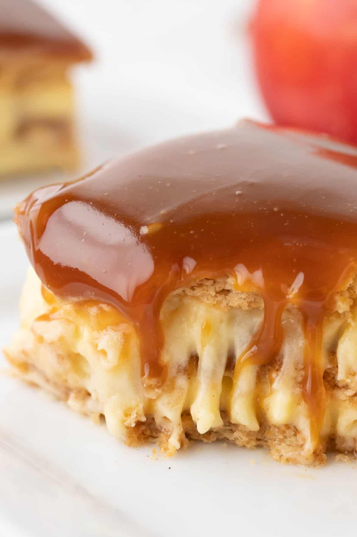 A close image of a piece of caramel apple eclair cake with a bite taken out of it.