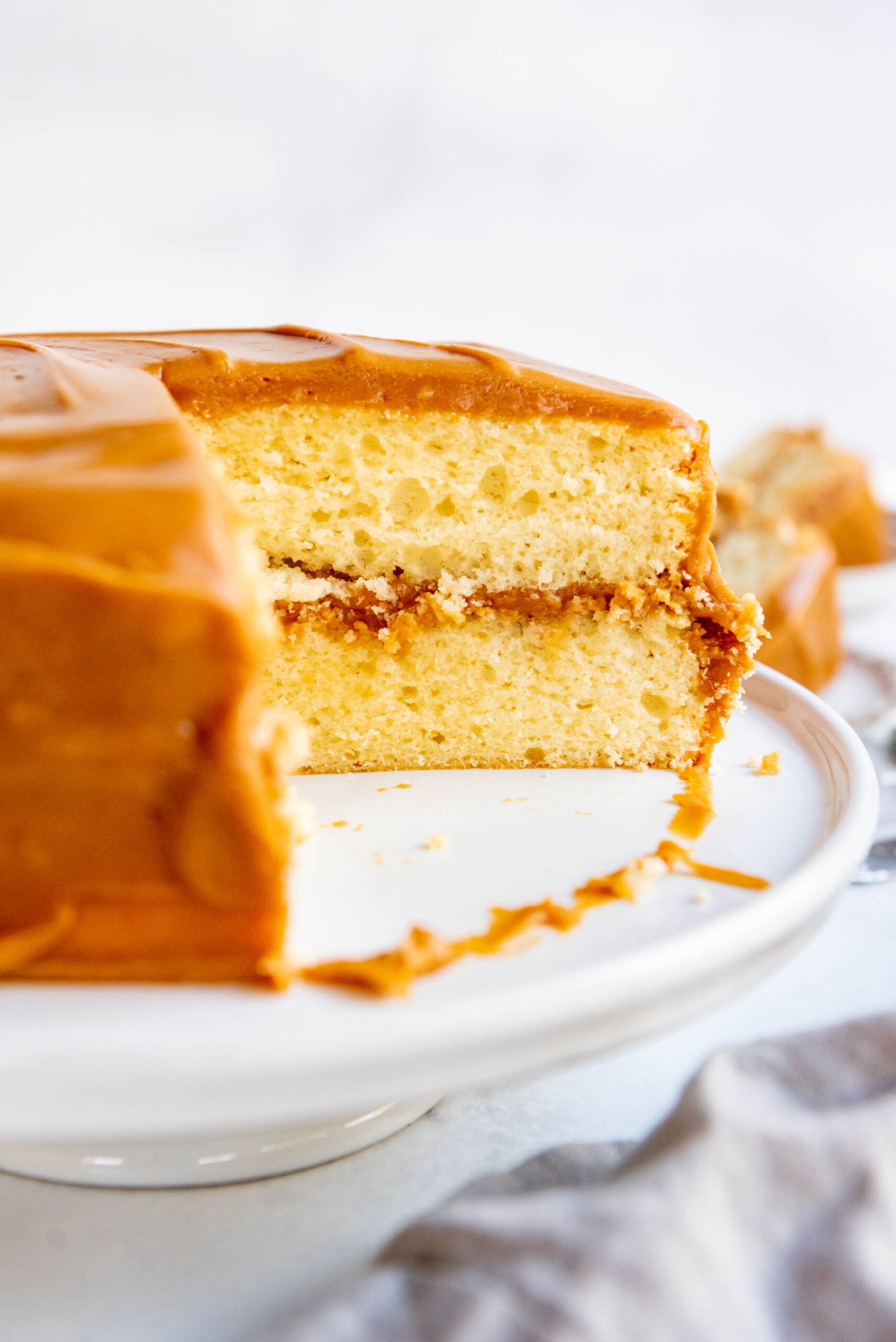 A side view of a caramel cake with a few slices removed.