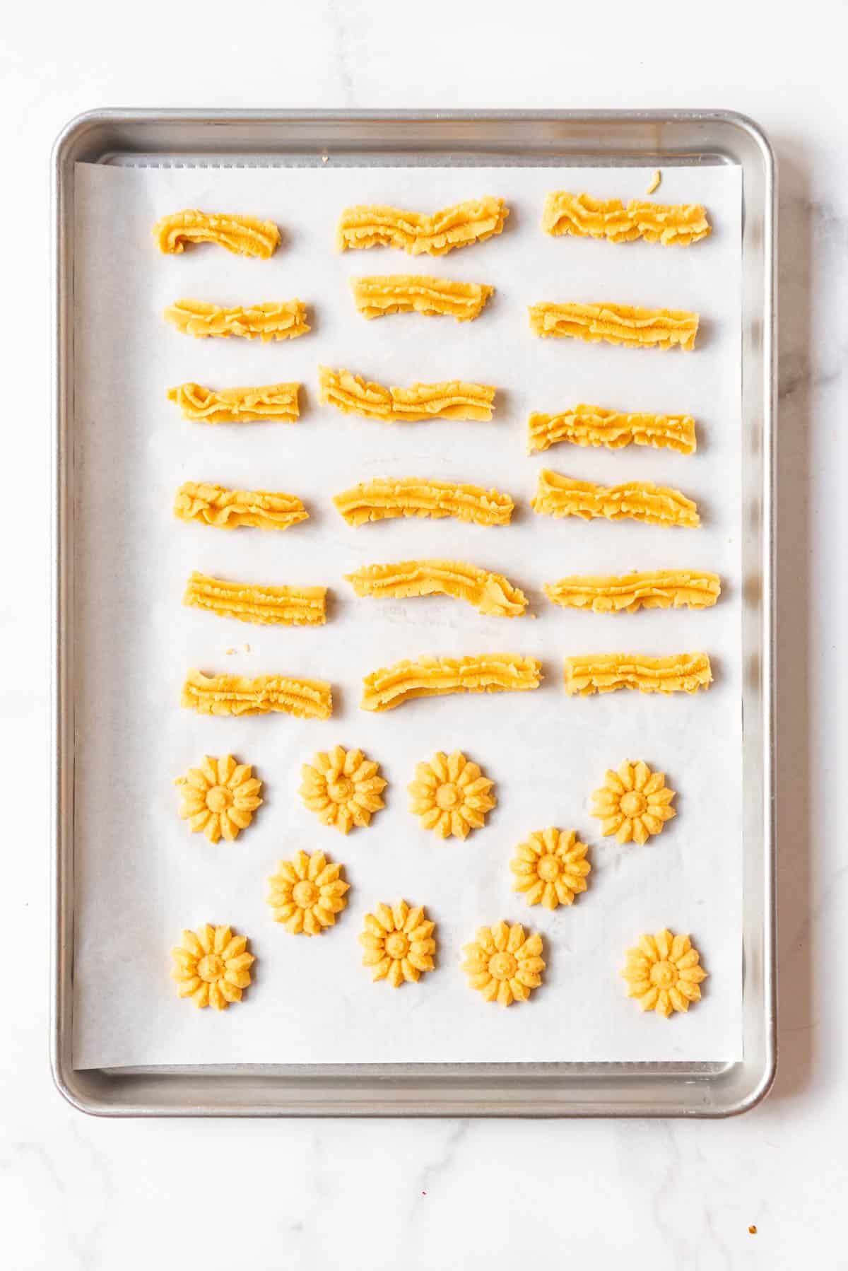 Piped cheese straws on a baking sheet with parchment paper.