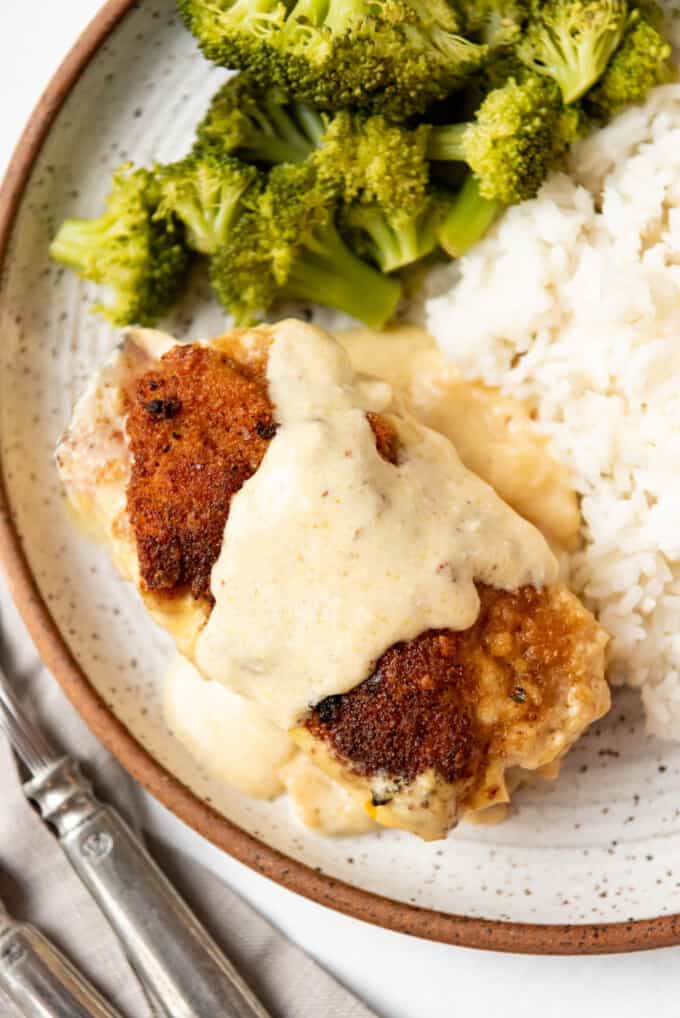 An overhead image of a piece of chicken cordon bleu with sauce on a plate.