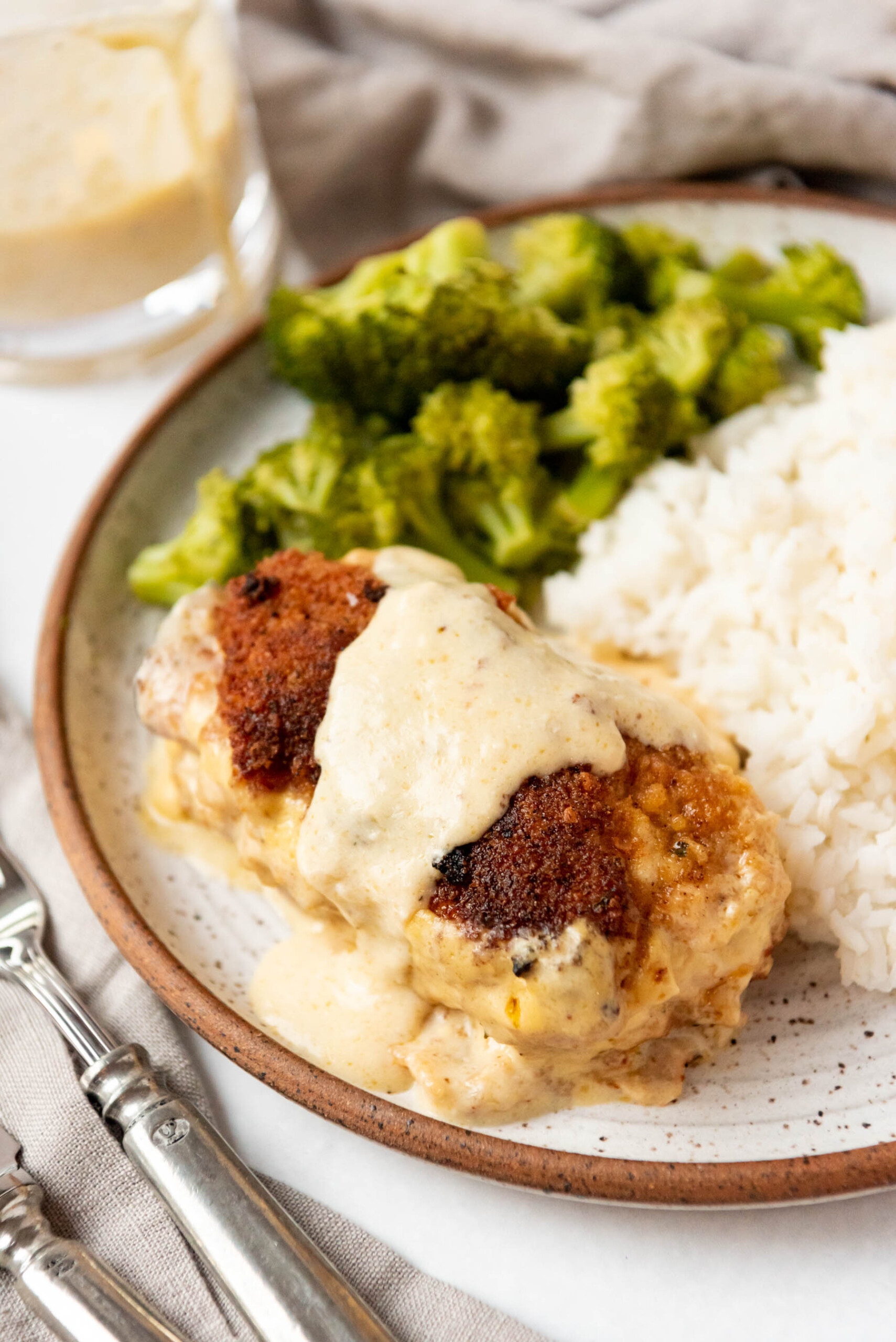 A serving of chicken cordon bleu on a plate with broccoli and rice.