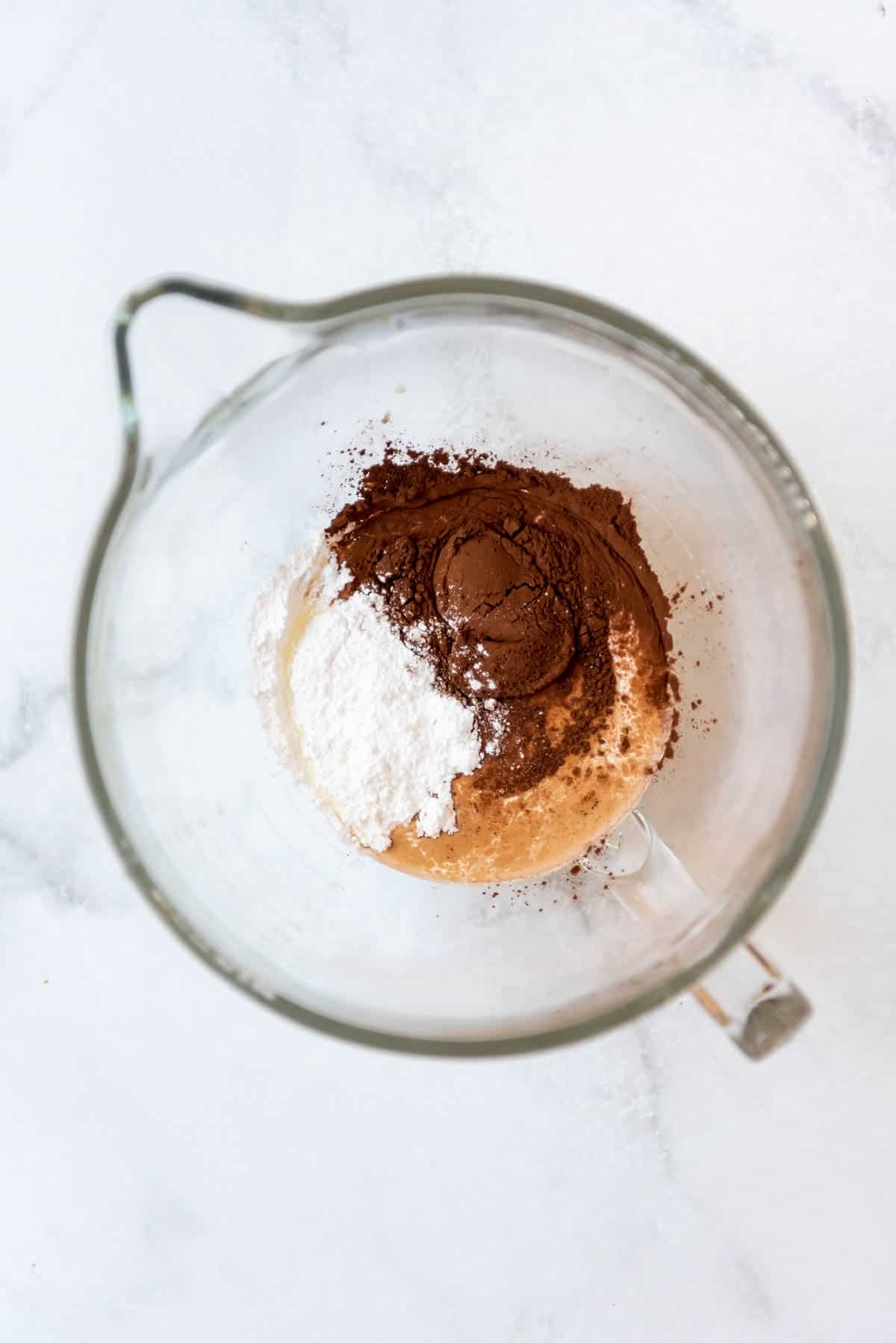 Combining sugar, cream, cocoa powder, and vanilla extract in a glass mixing bowl.