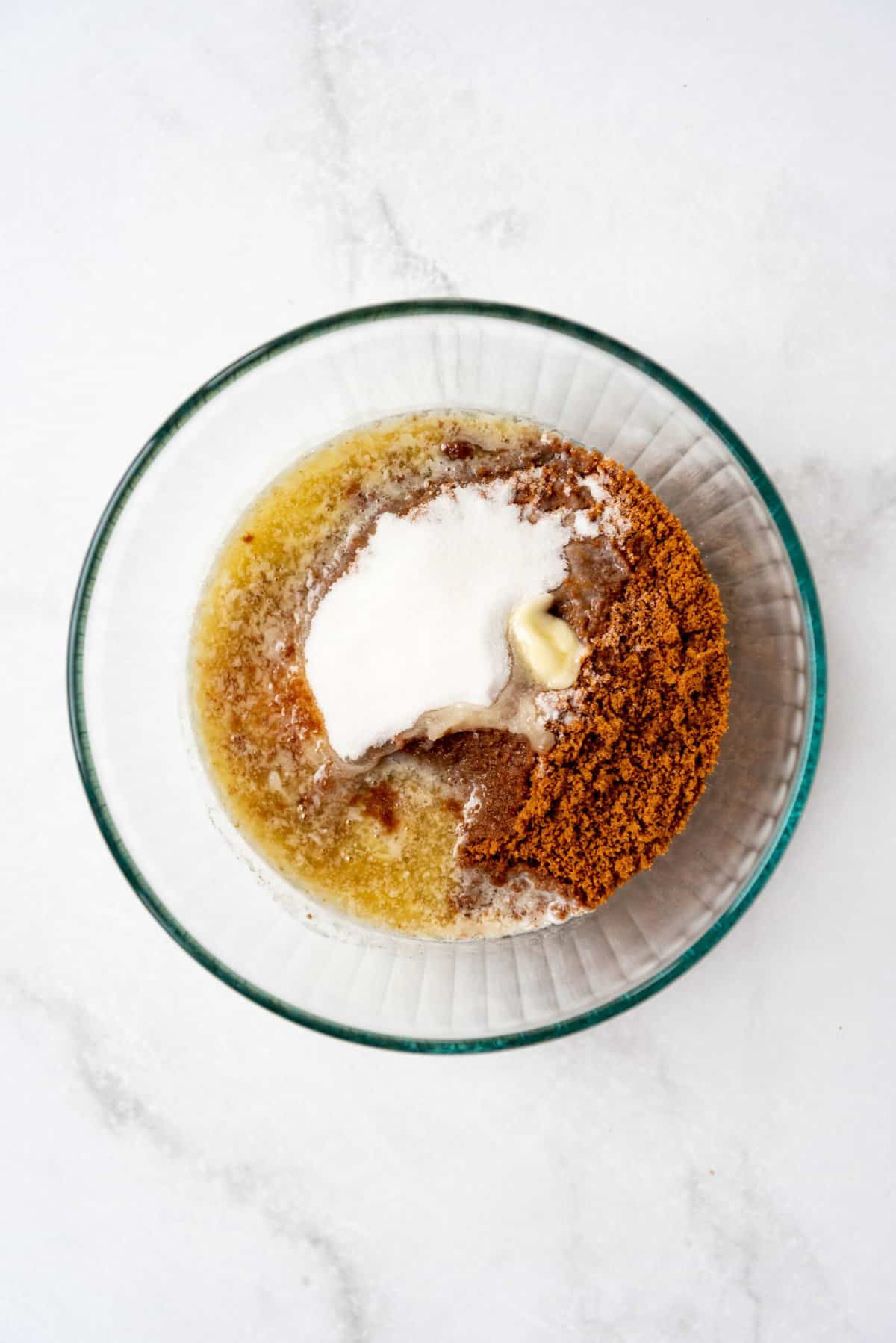 A glass bowl with biscoff crumbs, sugar, and melted butter.