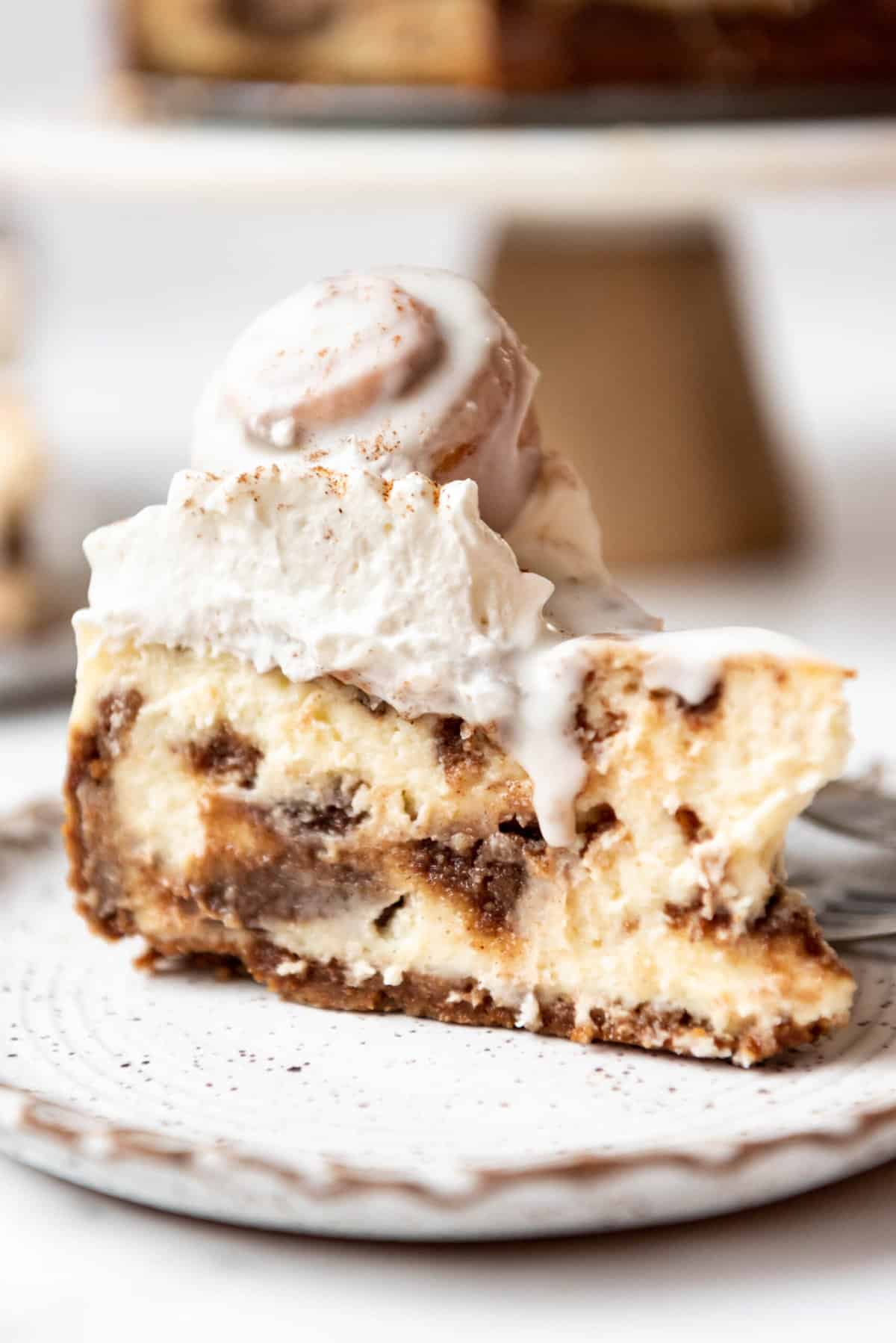A slice of cinnamon roll cheesecake on a plate.