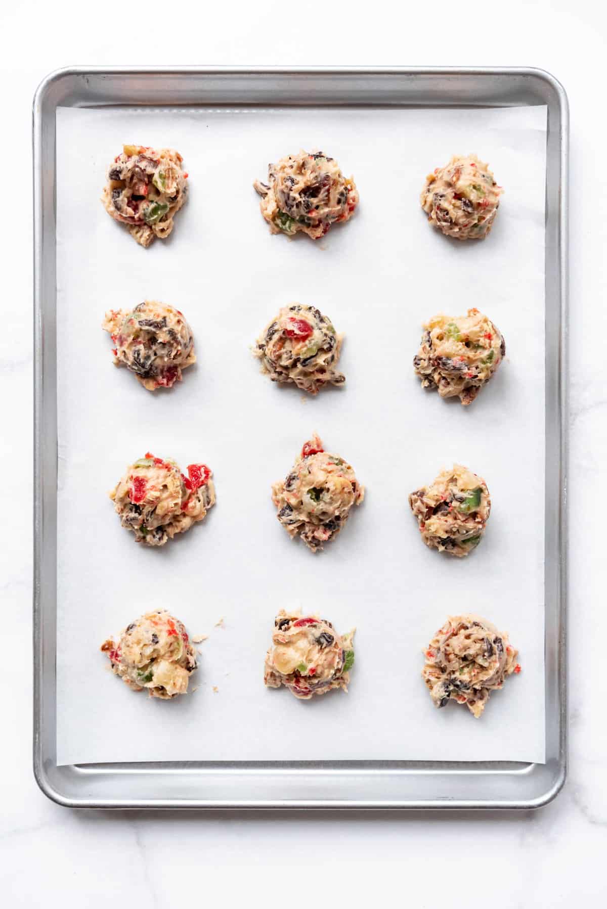 Fruitcake cookie dough on a baking sheet lined with parchment paper.